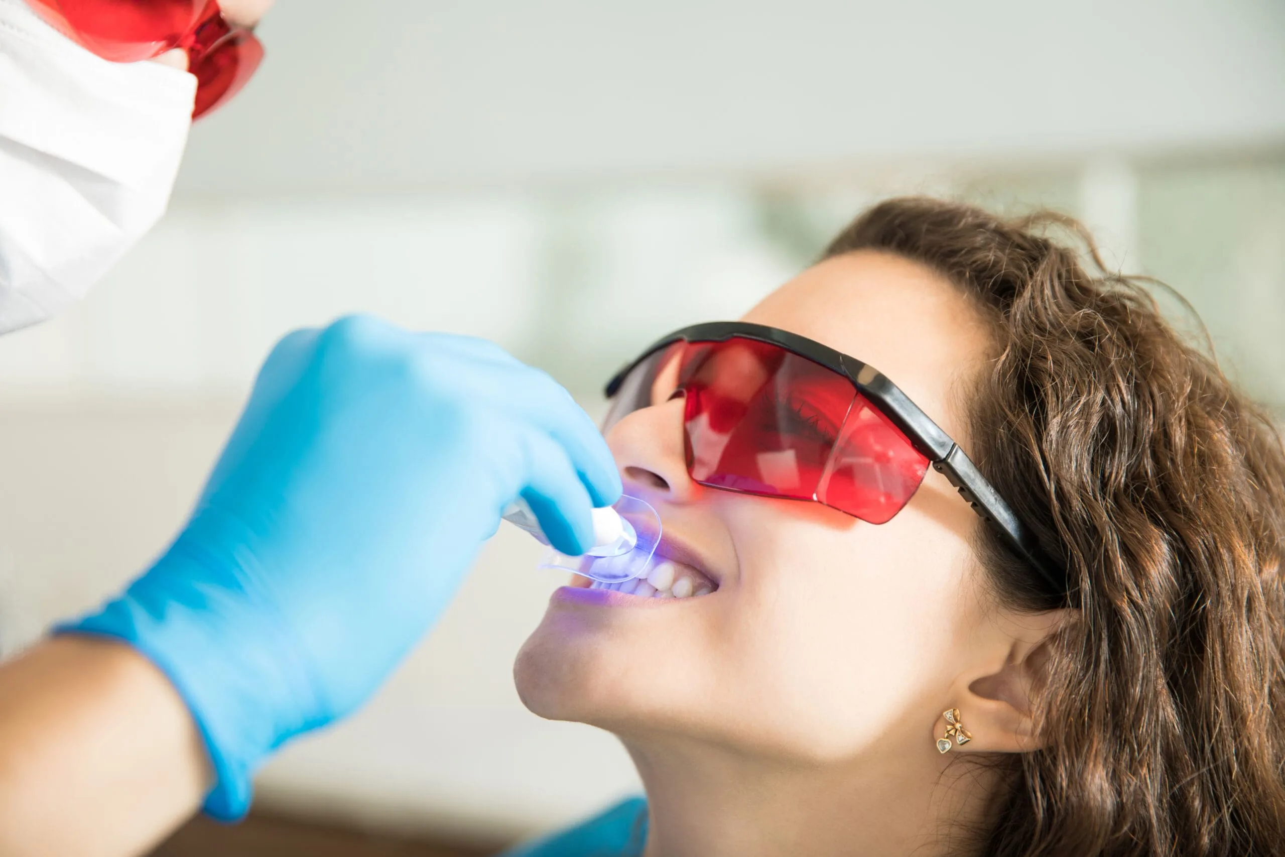 Woman Having Dental Checkup With Ultraviolet Light Dr. Monica Gobran & Associates pecializing in Implants, Invisalign, and Sleep Apnea | Zoom Whitening